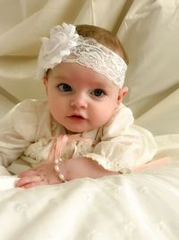 Portrait of cute baby girl lying on bed