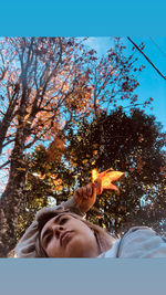 Low angle portrait of man by tree against sky