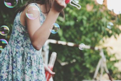 Midsection of woman blowing bubbles