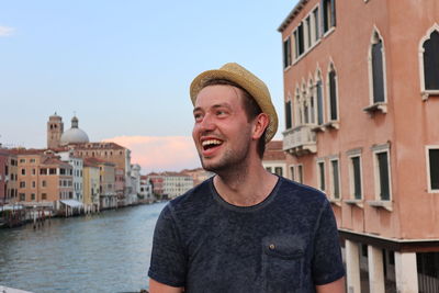 Smiling man standing against buildings in city