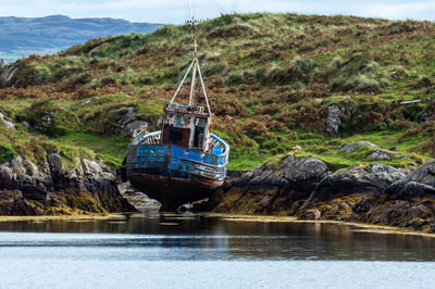 Boat on rock by river against mountain