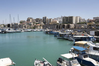 Boats moored in harbor by city against clear sky