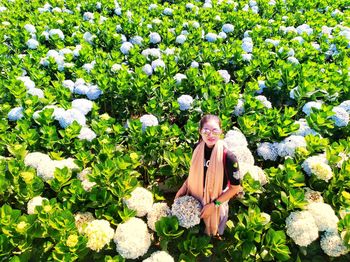 Young woman standing amidst flowers on field