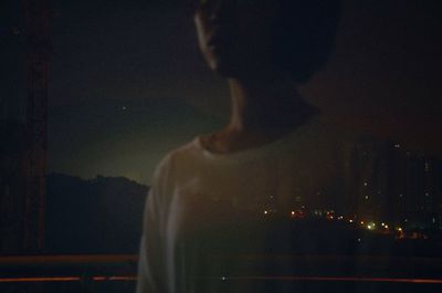 Man standing by illuminated city against sky at night