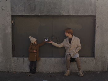 Side view of man standing against wall