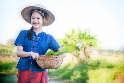 Portrait of a smiling young woman standing against plants