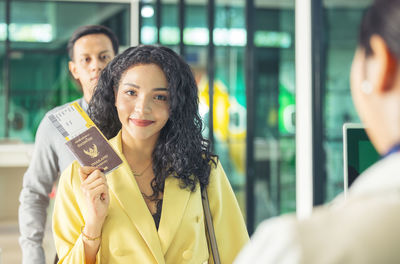 At the airport check-in counter, a passenger hands over his documents to the manager via a counter 