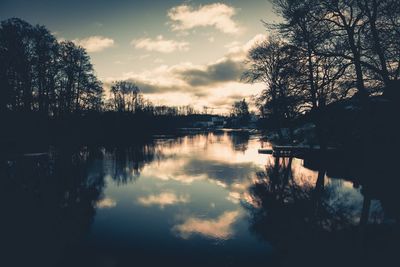 Reflection of silhouette trees in lake against sky at sunset