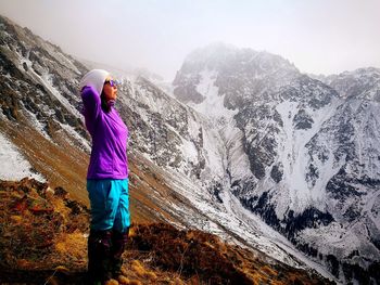 Side view of female hiker standing on mountain during winter