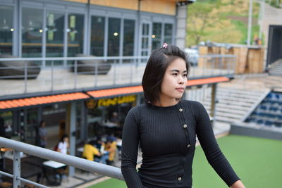 Thoughtful young woman looking away while standing by railing on observation point