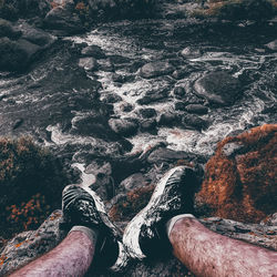 Low section of man relaxing on rock