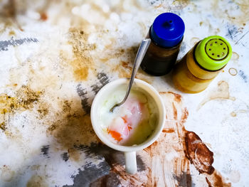 Half boiled eggs with soy sauce and pepper served in a cup on a stained table.