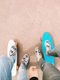 Low section of friends standing on skateboard outdoors