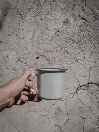 Midsection of person holding drink against wall