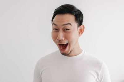 Portrait of young man standing against white background