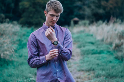 Young man holding sleeve while standing on field