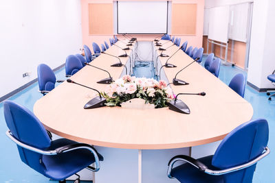 Empty chairs and table against white wall