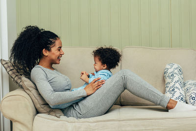 Mother and daughter sitting on sofa