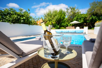 Chairs and table by swimming pool against sky