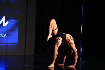 Side view of young woman sitting on stage