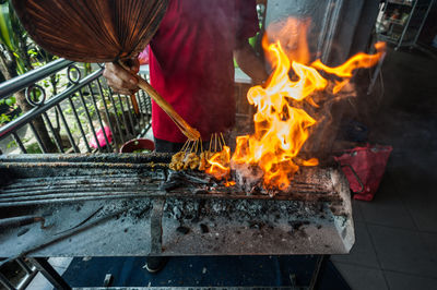 Midsection of man preparing meat on barbecue grill