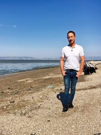 Portrait of man standing on shore against blue sky