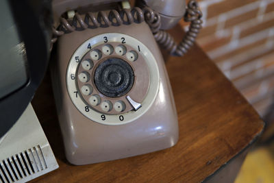 Vintage telephone on table against brick wall