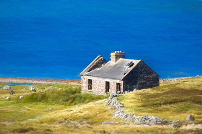 Abandoned house on field against blue sky