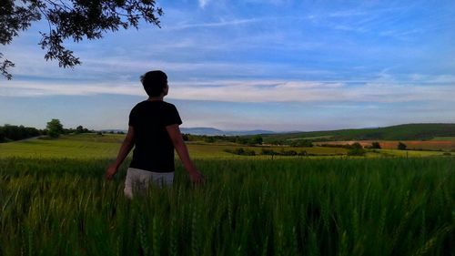 Rear view of woman standing on field against sky