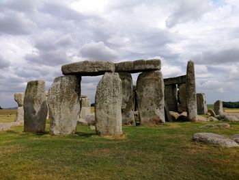 Stone structure on field against cloudy sky