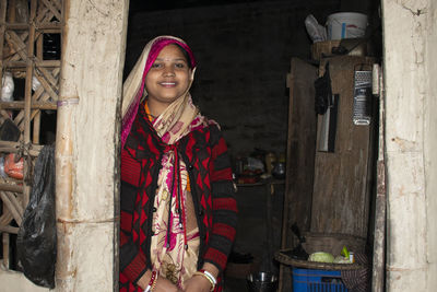 Portrait of smiling young woman in sari standing at the door of the house