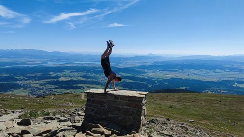 Rear view of man standing on mountain against sky