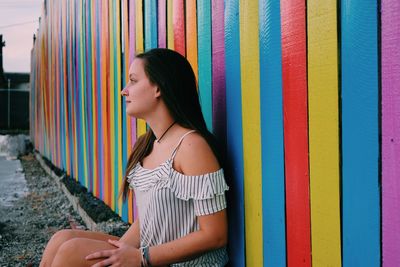 Young woman standing against multi colored wall