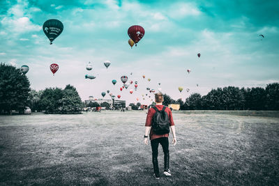 Rear view of people with balloons flying against sky