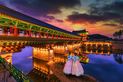 Illuminated bridge over lake during sunset