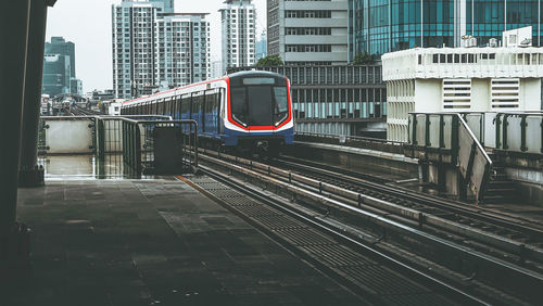 Train on railroad tracks by buildings in city