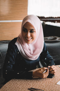 Portrait of smiling young woman sitting indoors