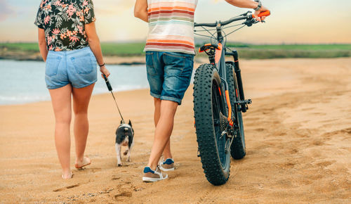 Unrecognizable couple with a fat bike taking a walk on the beach