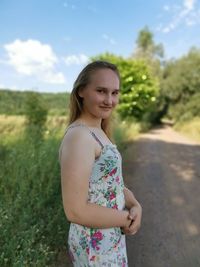 Portrait of smiling young woman standing against sky