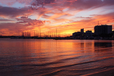 Scenic view of sea by buildings against sky during sunset