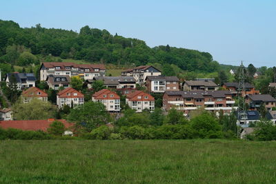 Houses on field by trees against sky