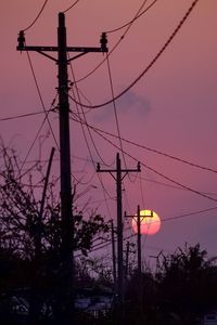 Low angle view of electricity pylon against sky during sunset
