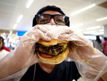 Man wearing gloves eating hamburger at restaurant