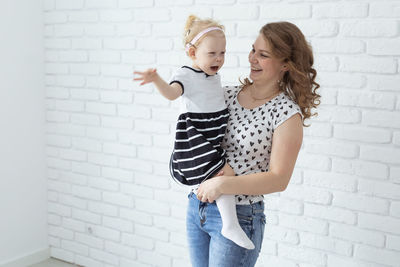 Portrait of smiling young woman standing against wall