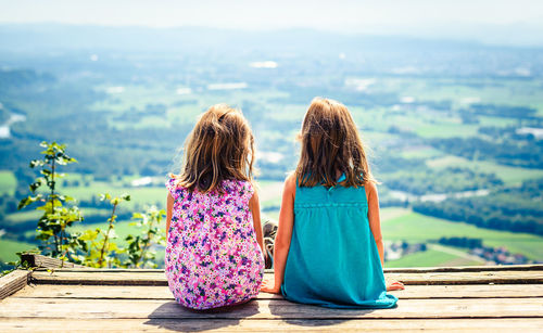 Sisters sitting against landscape