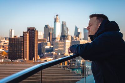 Man looking at city buildings against sky