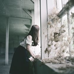 Side view of woman looking through window