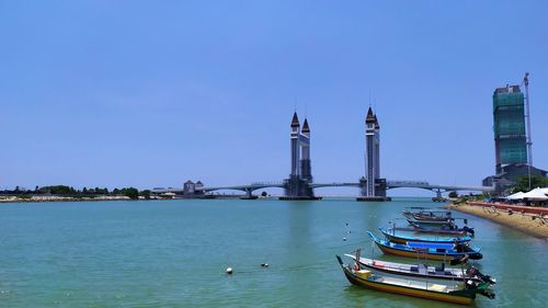 Sailboats in sea against sky in city