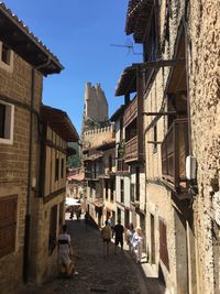 People walking on alley amidst buildings in city