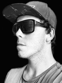 Portrait of young man wearing sunglasses against black background